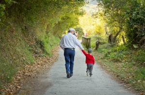 Grandfather and grandchild walking in nature path
