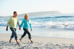 Senior Couple Walking Along Beach