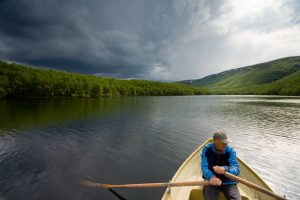 Senior fisherman rowing in a boat on a lake Mikkeljavre in Norwa