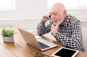 Senior man talking on phone with laptop